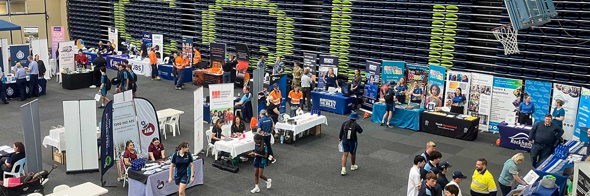 Students browse stalls at a careers expo inside a sports arena