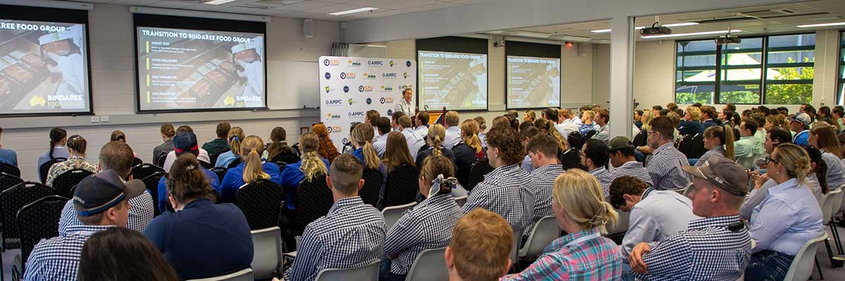 A room full of people watch a woman deliver a presentation at the ICMJ Northern Conference