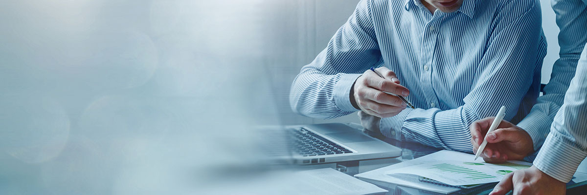 Two people look over business documents at a desk