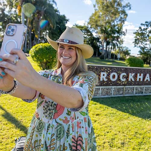 A woman takes a selfie in front of Rockhampton welcome sign